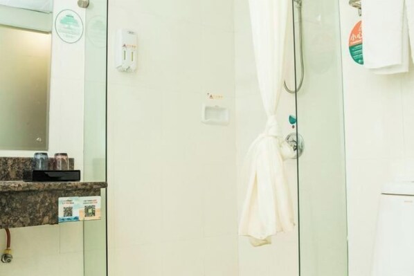 Ein Badezimmer mit Duschkabine aus Glas, einem Handtuch an der Wand und einer Seifenspender.