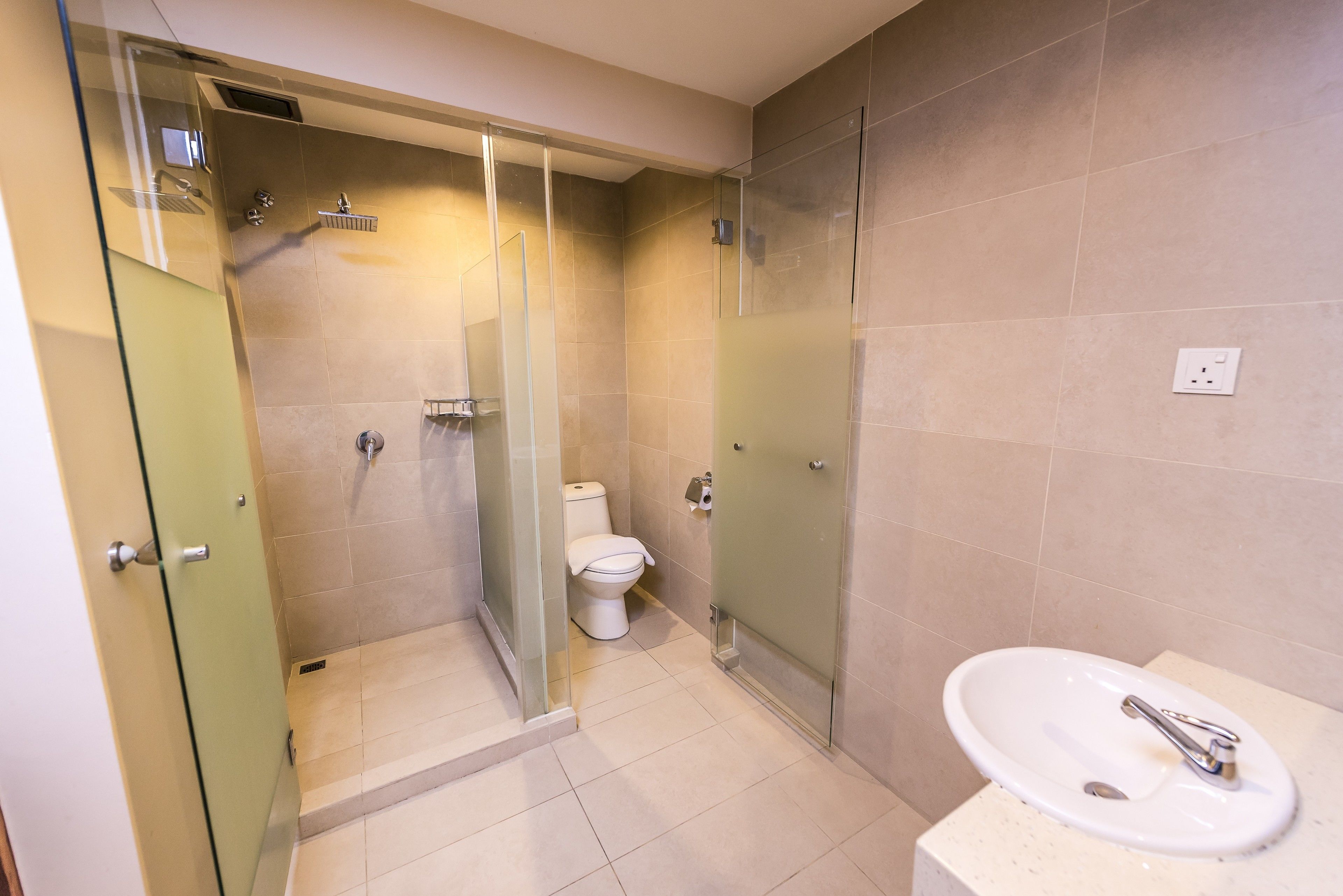 A modern bathroom with a glass-enclosed shower, a toilet, and a sink.