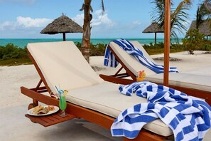 Am Strand, weißer Sandstrand, Liegestühle, Sonnenschirme