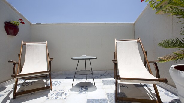 Un pequeño patio con dos sillones, una mesita redonda y una planta en maceta.