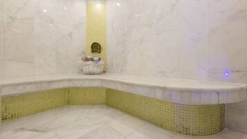 Ein Badezimmer mit einer Eckbadewanne, gelb gefliesten Wänden und einem Marmorboden.
