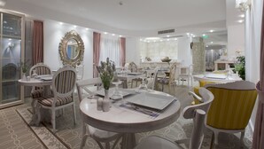 Un comedor bien iluminado con mobiliario blanco, un espejo grande y una pared de piedra.