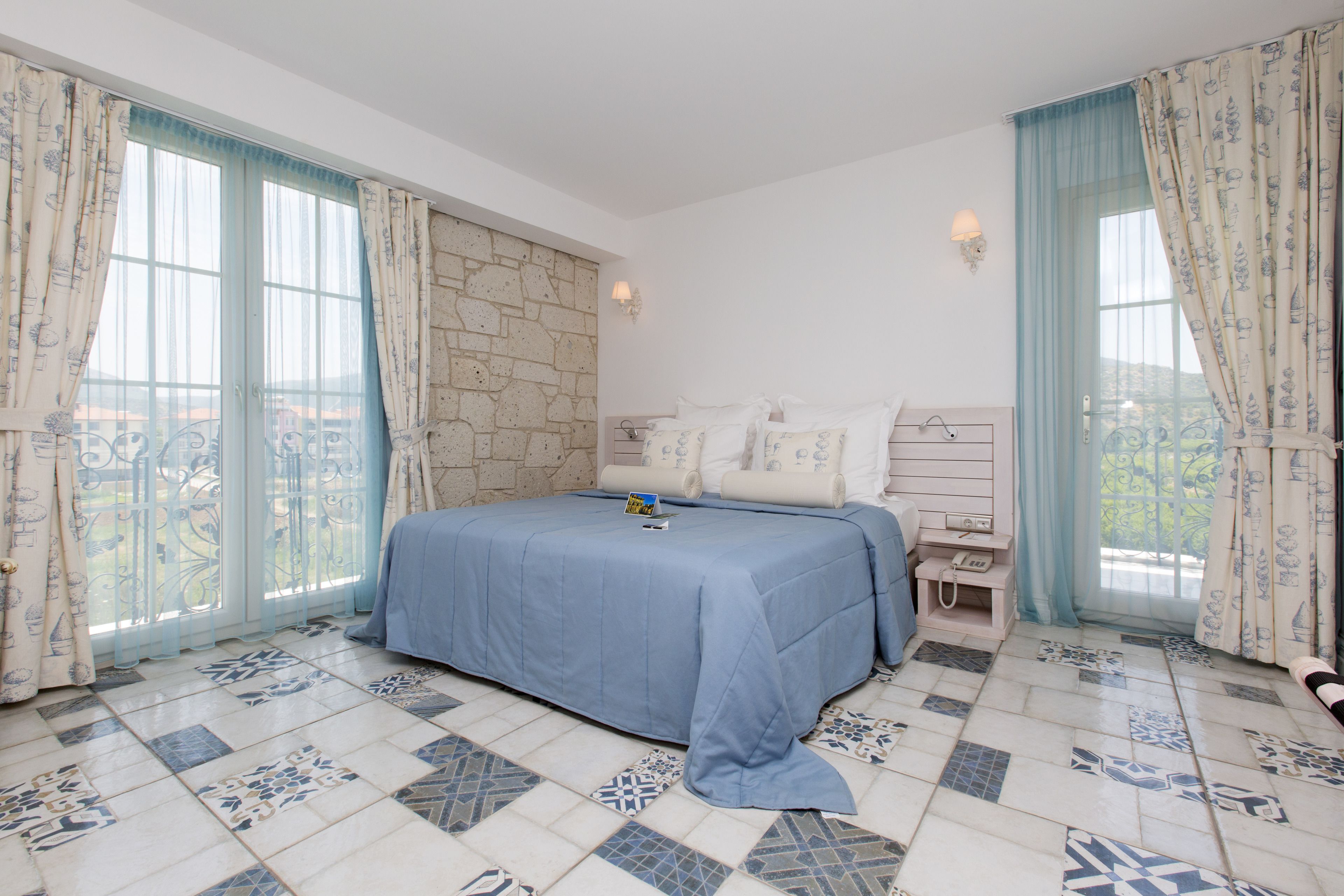 Un dormitorio con una cama grande, una mesita de noche, una lámpara y vistas al exterior.