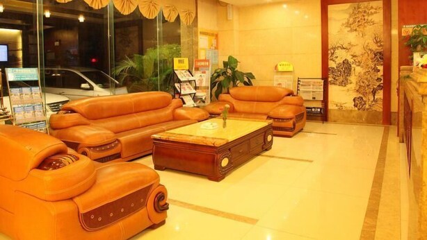Un vestíbulo con sofás de cuero, una mesa de centro de madera y un mostrador de recepción.