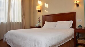A hotel room with a large bed, two bedside lamps, a nightstand, and a window with curtains. - GreenTree Inn BengBu HuaiHe Road Pedestrian Street Hotel (Bengbu)