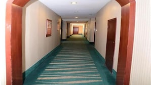 A hotel hallway with a green carpet, wooden doors, and framed pictures on the walls. - GreenTree Inn BengBu HuaiHe Road Pedestrian Street Hotel (Bengbu)