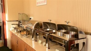 A buffet setup with multiple serving stations, including hot and cold food options, arranged on a counter with a wooden cabinet below. - GreenTree Inn BengBu HuaiHe Road Pedestrian Street Hotel (Bengbu)