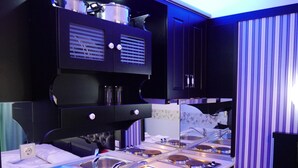 A modern kitchen with stainless steel appliances, black cabinetry, and a striped curtain. - Blue Sky Apartments (Thasos)