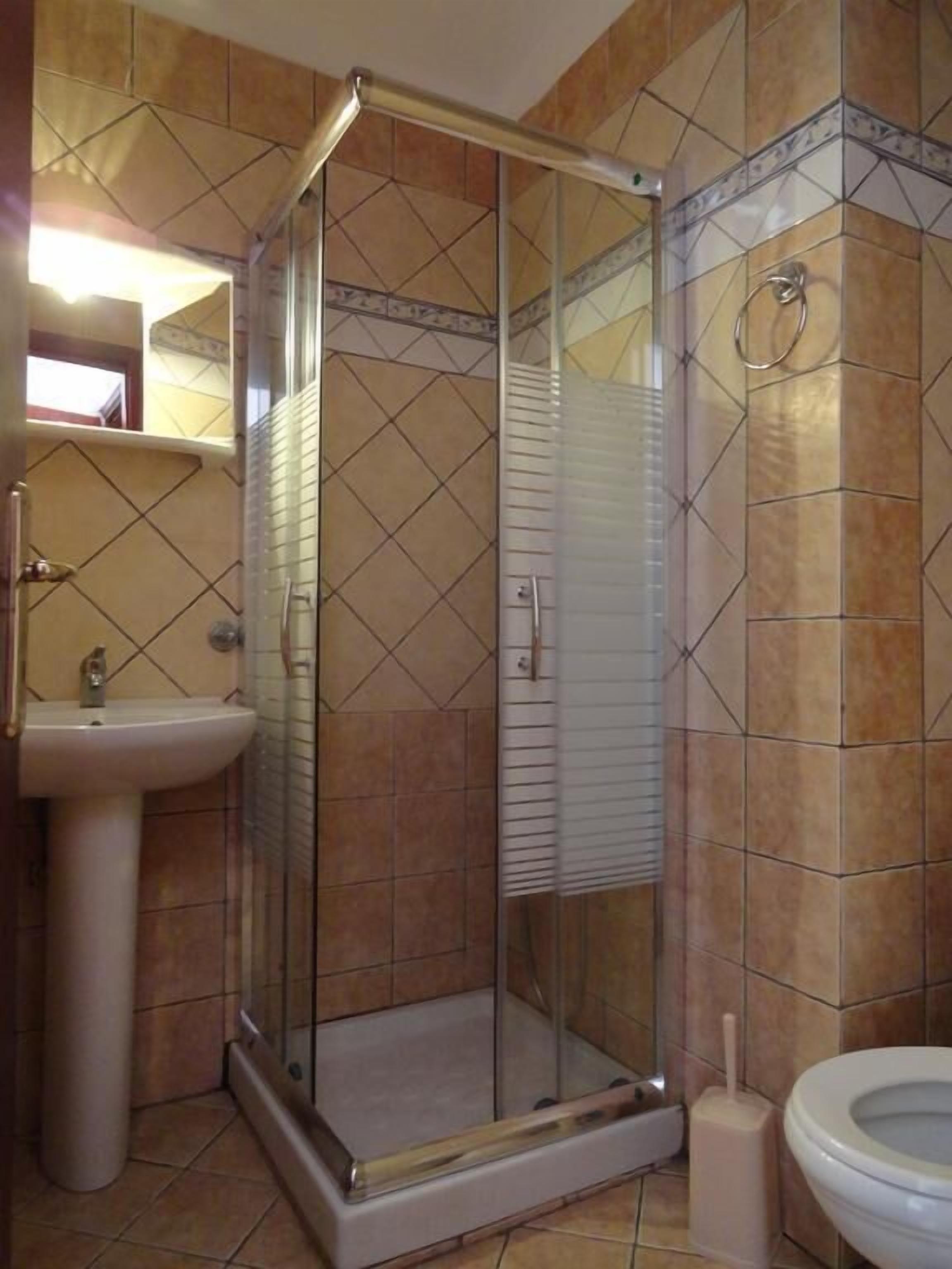Een badkamer met een douchecabine van glas, een wastafel en een toilet.
