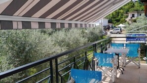 A balcony with a striped awning, outdoor seating, and a sign for 'Blue Boutique'. - Blue Sky Apartments (Thasos)
