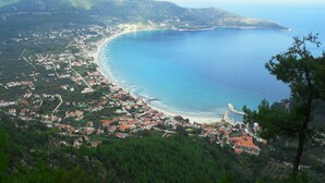 A coastal town with a beach, houses, and a forested hill. - Blue Sky Apartments (Thasos)