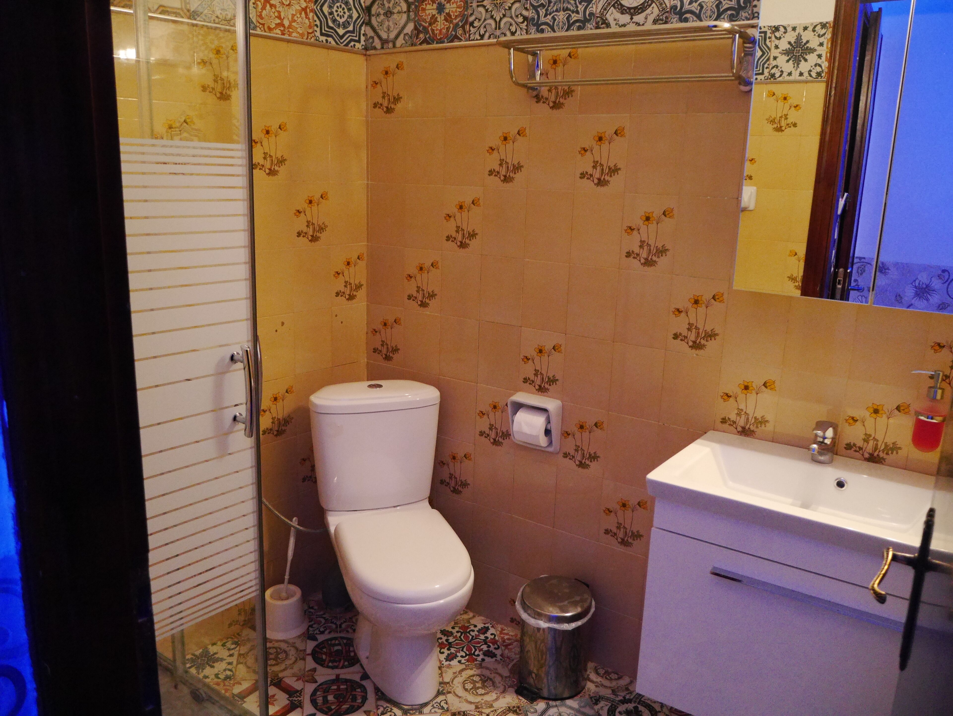 A bathroom with a toilet, sink, and a mirror.