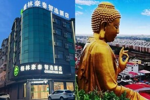 Experience the serene atmosphere of Green Tree Intelligent Hotel, surrounded by a tranquil cityscape and a majestic golden Buddha statue.