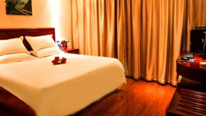 A hotel room with a large bed, a wooden headboard, a desk with a computer, and a window with curtains. - GreenTree Inn Smart Selection Hotel (Guanyun Wenzhou Trade City Jiulong Square Branch) (Lianyungang)