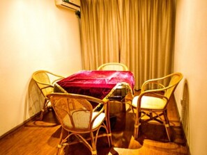 A small room with a wooden floor, a table with a red tablecloth, two wicker chairs, and a beige curtain. - GreenTree Inn Smart Selection Hotel (Guanyun Wenzhou Trade City Jiulong Square Branch) (Lianyungang)