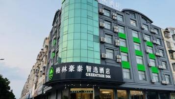 A hotel building with a curved facade, a prominent green-lit corner, and signage for the GreenTree Inn.