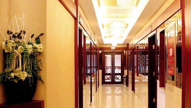 A hotel corridor with a polished floor, wooden doors, and a chandelier. - GreenTree Inn Huaian Chuzhou Avenue Zhou Enlai Memorial Hall Hotel (Huai'an)