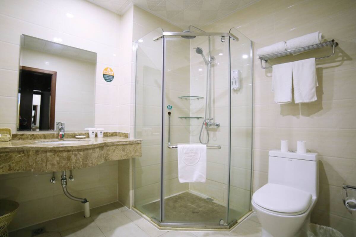 A bathroom with a glass-enclosed shower, a toilet, and a sink with a mirror.