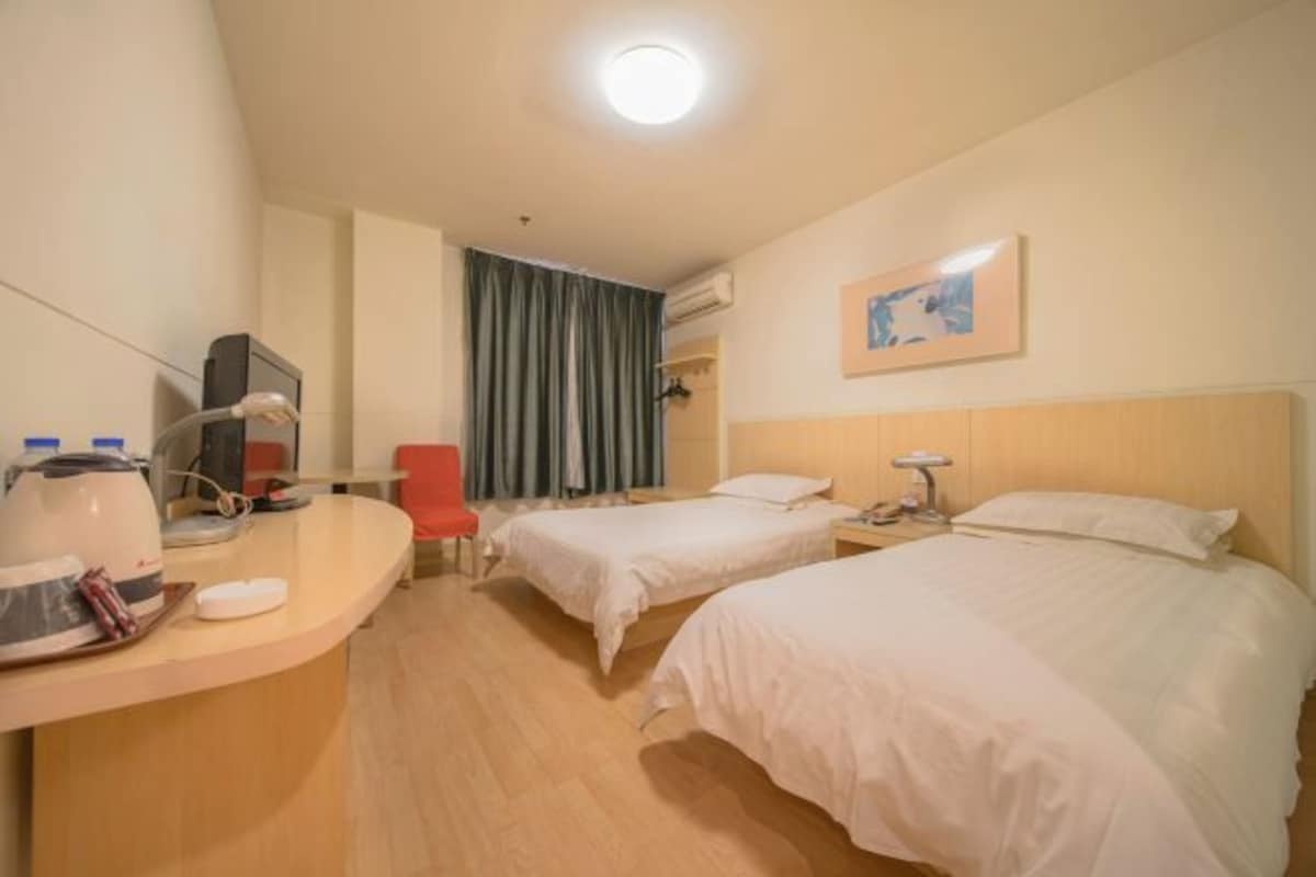 A hotel room with two beds, a desk with a chair, a coffee maker, and a TV.
