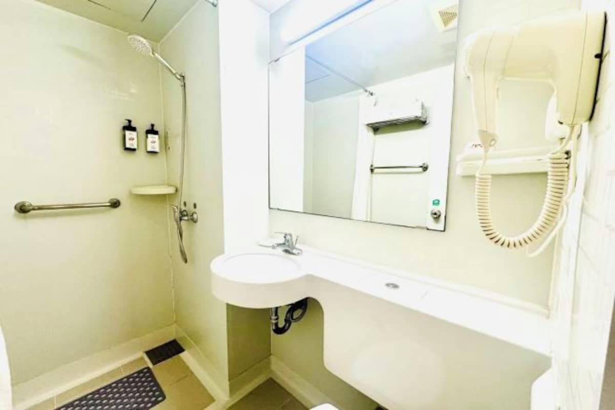 A bathroom with a shower, toilet, sink, and a mirror.