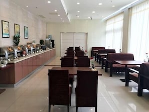 A restaurant with a long counter, multiple tables, and chairs. - Jinjiang Inn Taicang Shanghai Lu (Suzhou)