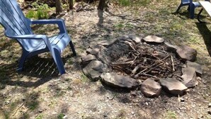 A campsite with a fire pit surrounded by rocks and two blue chairs. - Lake Wanoka Resort (Honesdale)