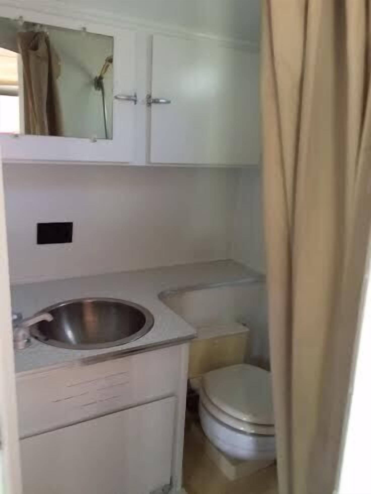 Un baño pequeño con lavamanos, espejo y retrete blancos.