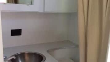A compact bathroom with a white sink, mirror, and toilet.
