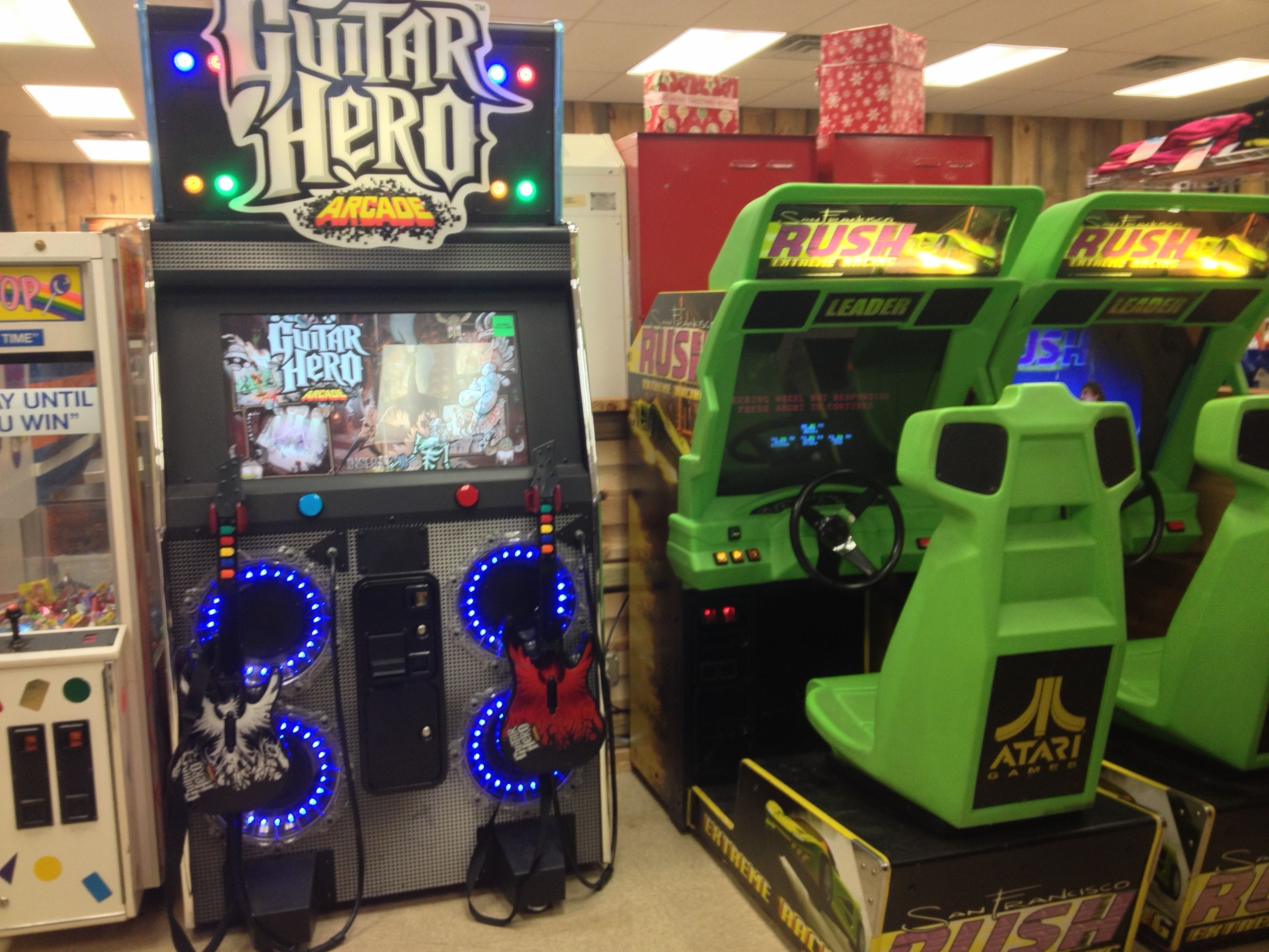 Una hilera de máquinas de arcade, incluyendo Guitar Hero y Rush, en una zona de juegos.