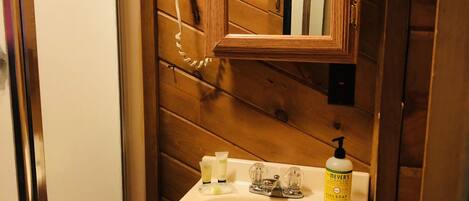 Une salle de bain avec un lambris en bois, un lavabo blanc et un sèche-cheveux posé sur un support.