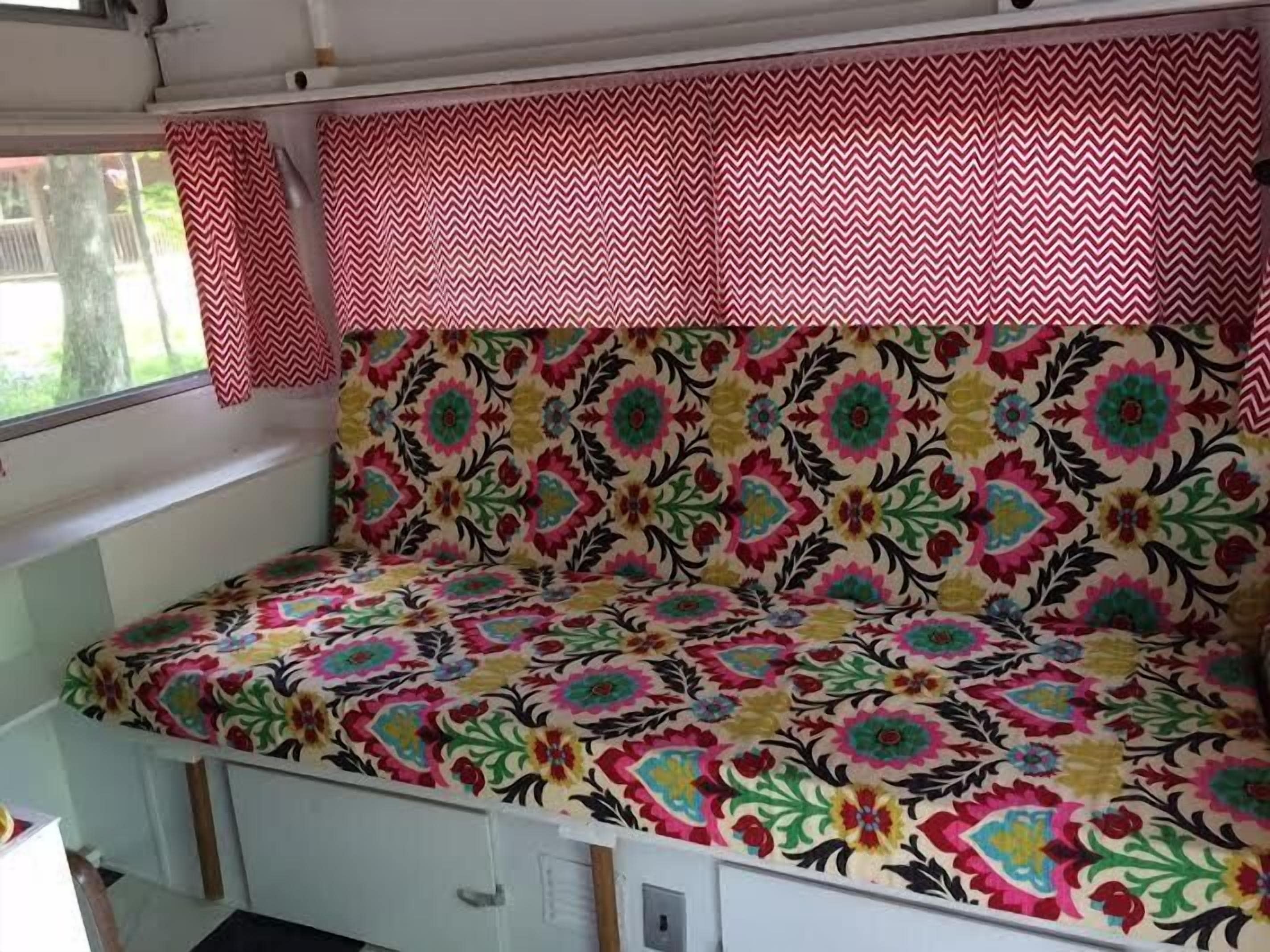 Een klein, afgesloten hoekje met een kleurrijke bank met bloemenprint en een rood-wit geblokt gordijn.