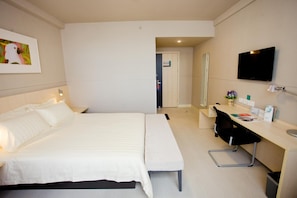 A hotel room with a bed, a desk, a chair, a TV, and a mirror. - Jinjiang Inn - Sanya Hexi Road Pedestrian Street Hejing (Sanya)