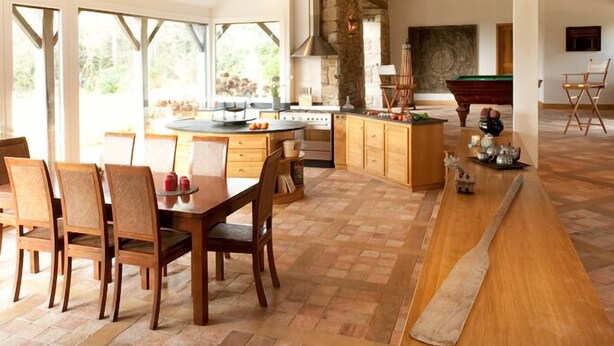 Um amplo quarto estilo loft, com vigas de madeira aparentes, área de jantar, cozinha e mesa de bilhar.
