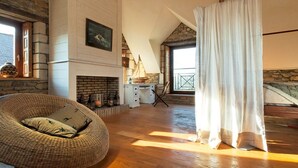 Um quarto aconchegante com lareira, uma poltrona de vime e vista para o exterior.