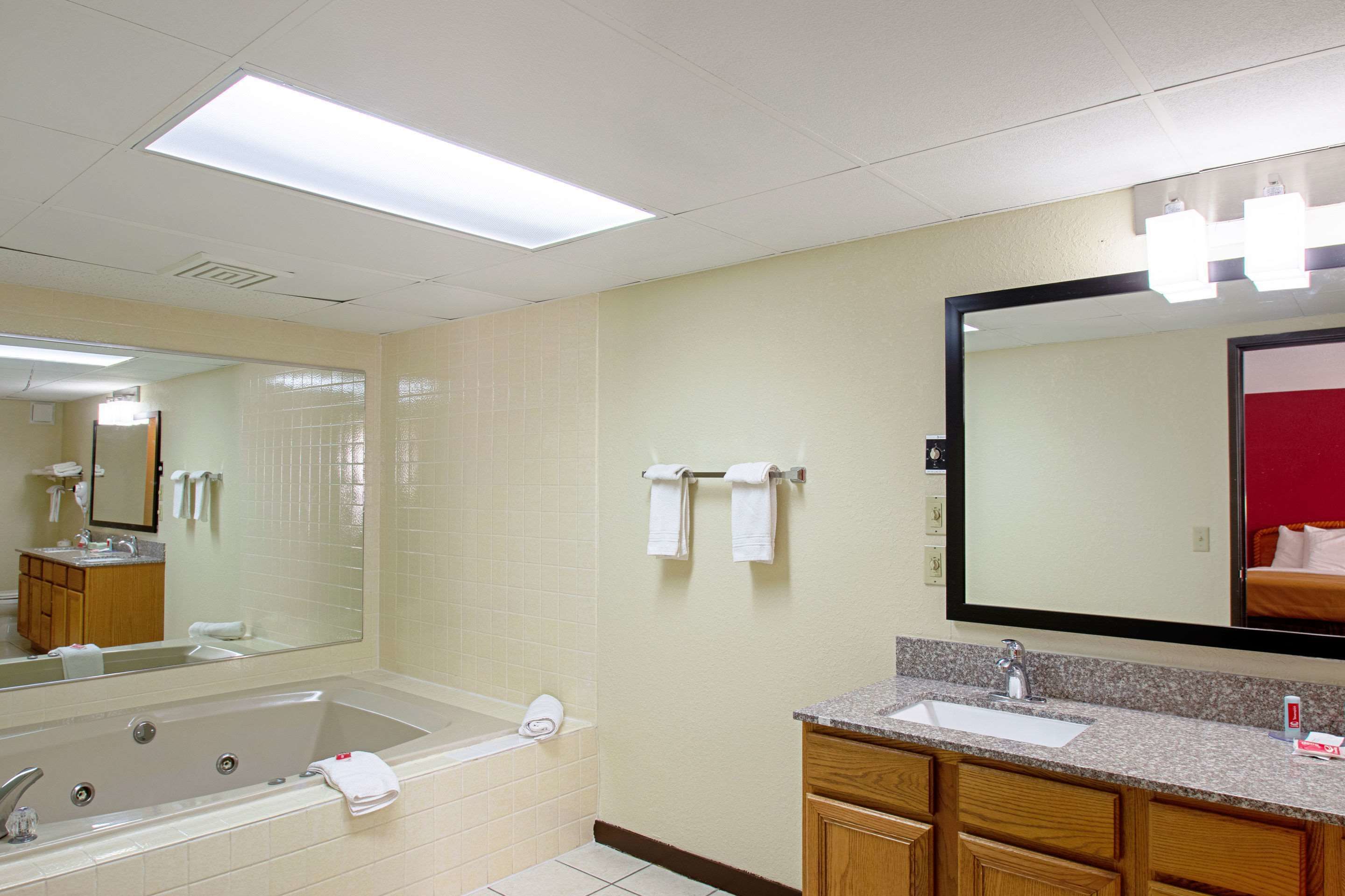 A hotel bathroom with a large bathtub, a sink, and a mirror.