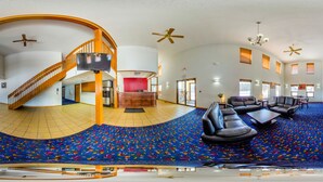 Un amplio salón con techo curvo, una escalera y una alfombra grande y colorida.