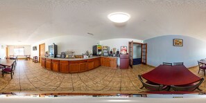 A spacious room with a curved wooden counter, a dining table, and a red boat-shaped table.
