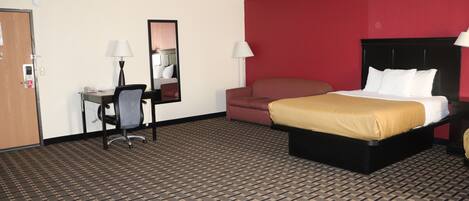 Habitación de hotel con cama, escritorio, silla y una pared decorada en rojo.
