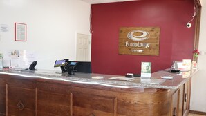 Una recepción con detalles de madera, una pantalla digital y un cartel que dice 'Econom Lodge'.