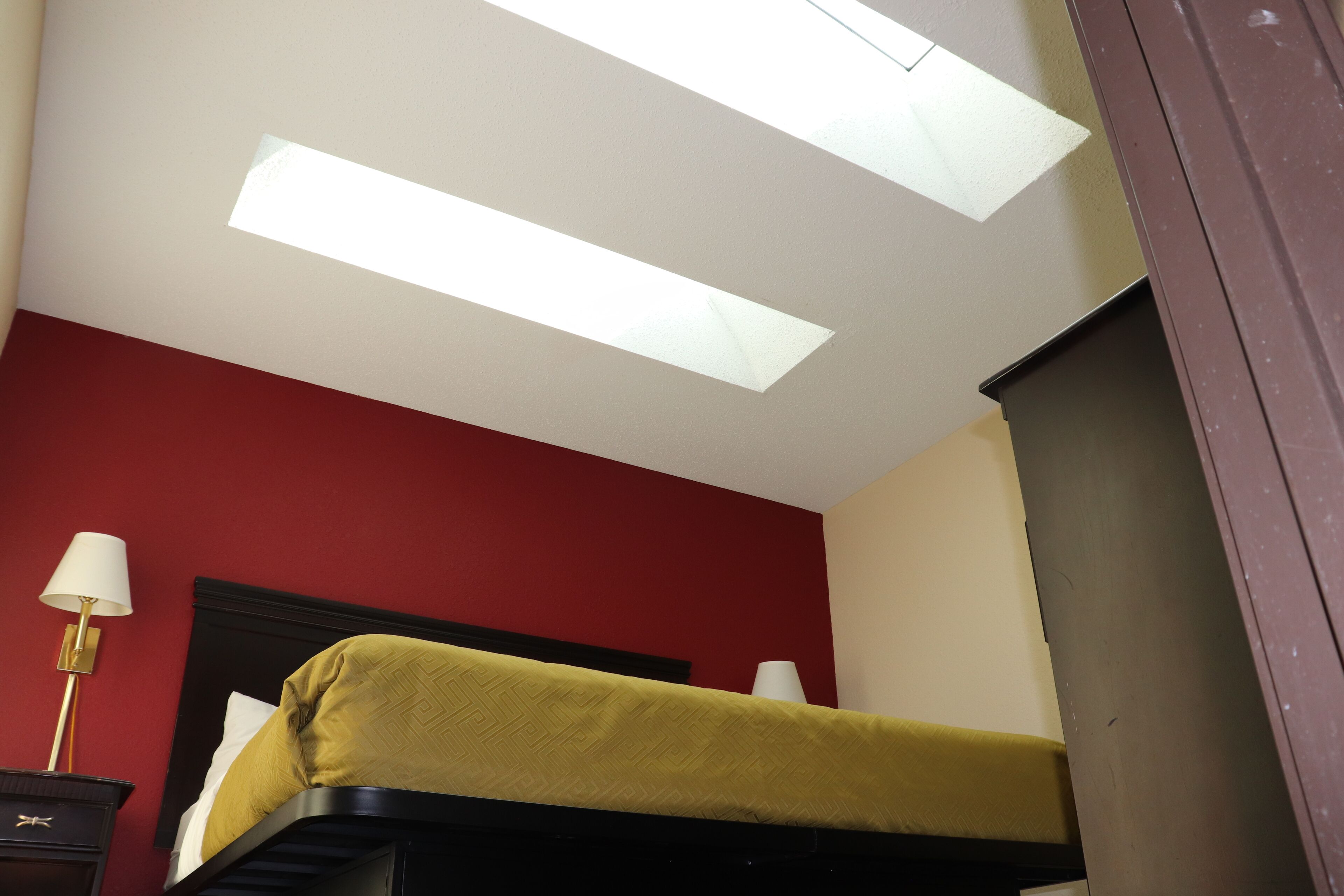 A room with a bunk bed, a nightstand with a lamp, and a ceiling light fixture.