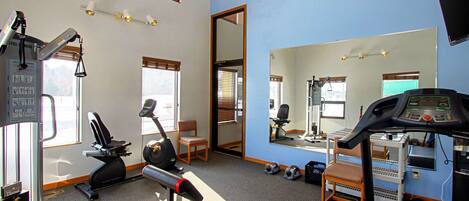 A gym with exercise equipment, a mirror, and a treadmill.