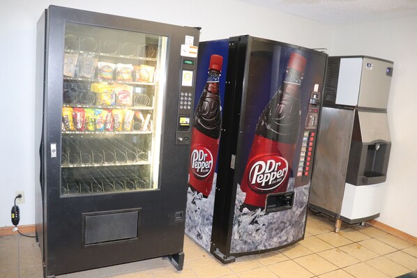 A vending machine with a Dr Pepper logo and a refrigerator.