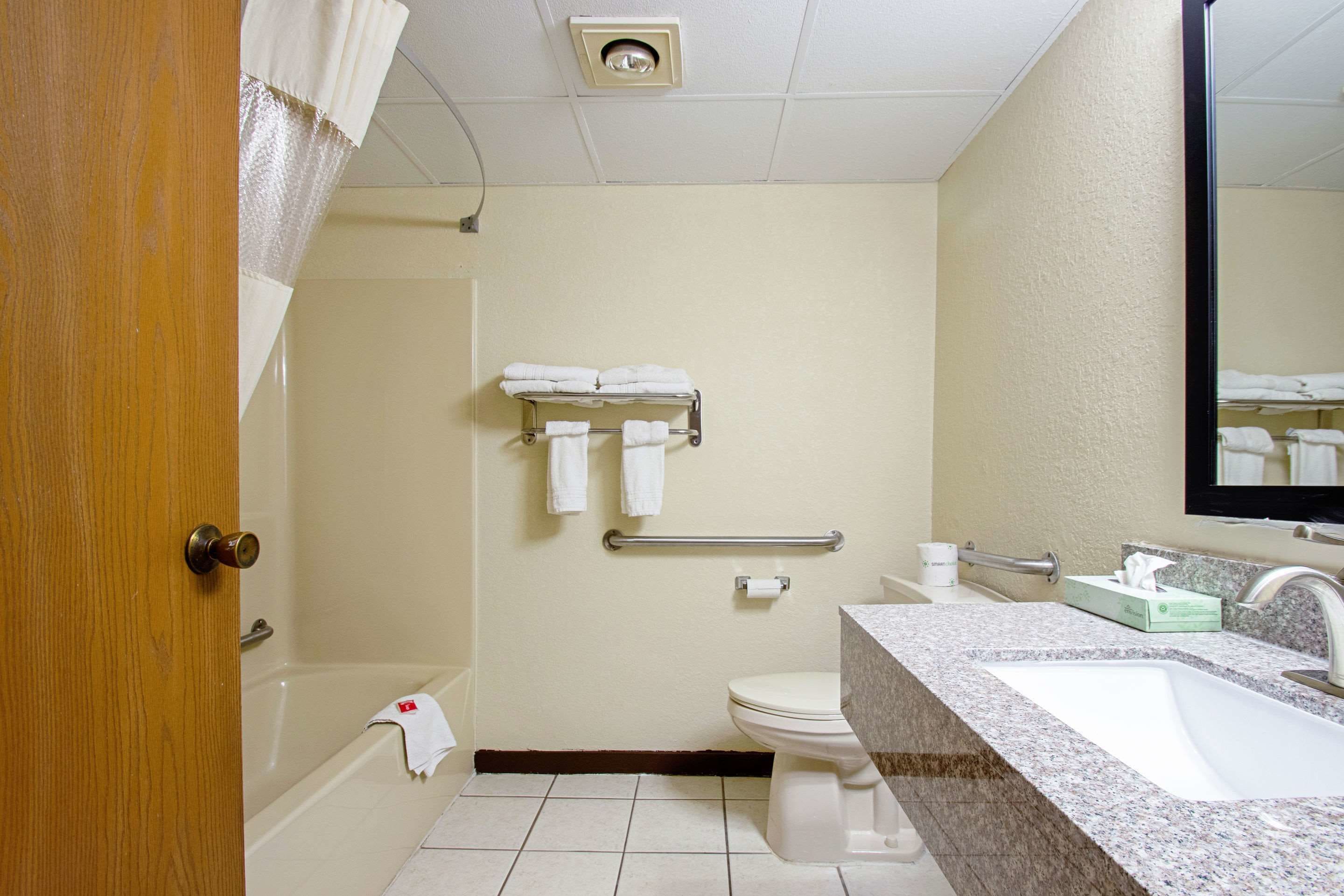 A bathroom with a bathtub, toilet, sink, and a towel rack with towels.