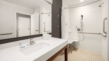 Un baño moderno con lavamanos, espejo y ducha blancos.