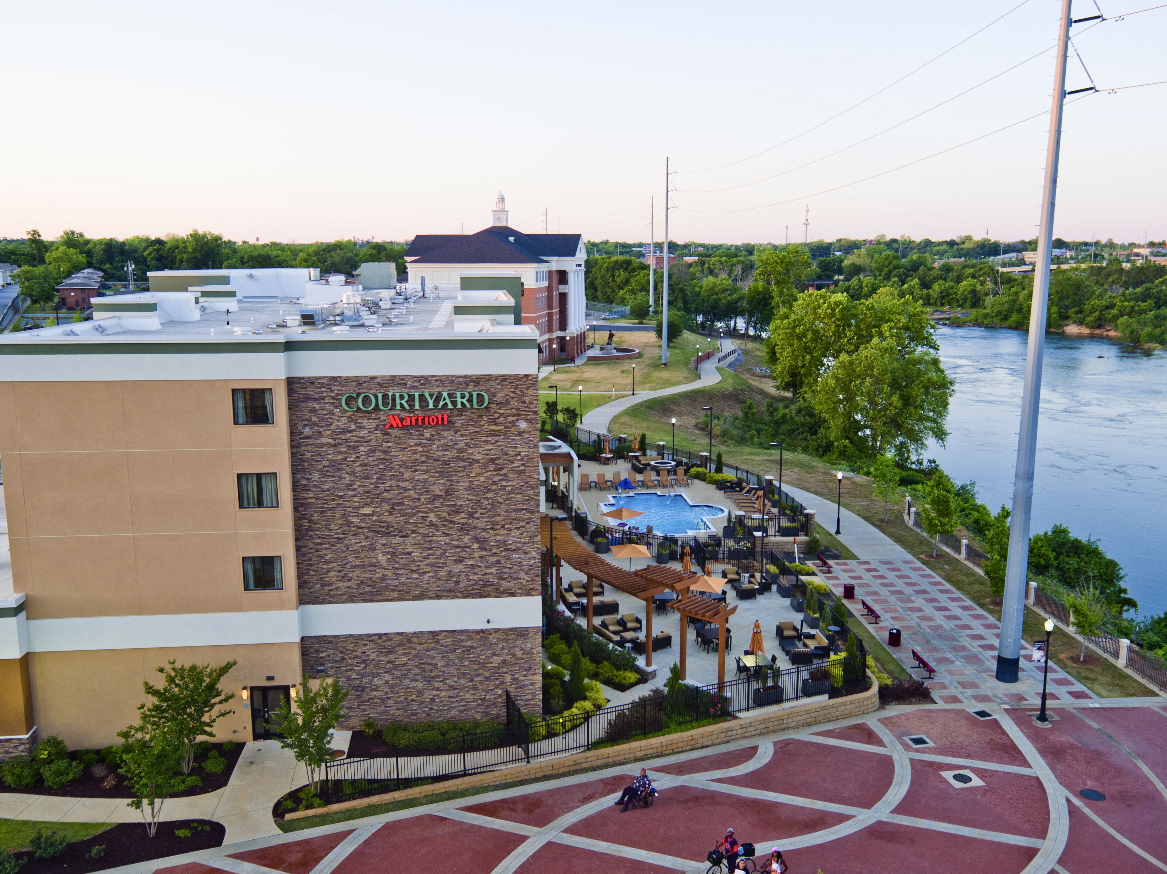 A Courtyard Marriott hotel with a rooftop pool, outdoor seating, and a view of a river.