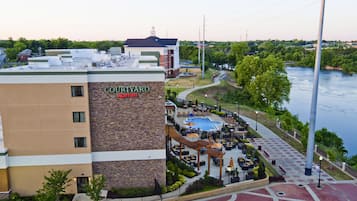 A Courtyard Marriott hotel with a rooftop pool, outdoor seating, and a view of a river.