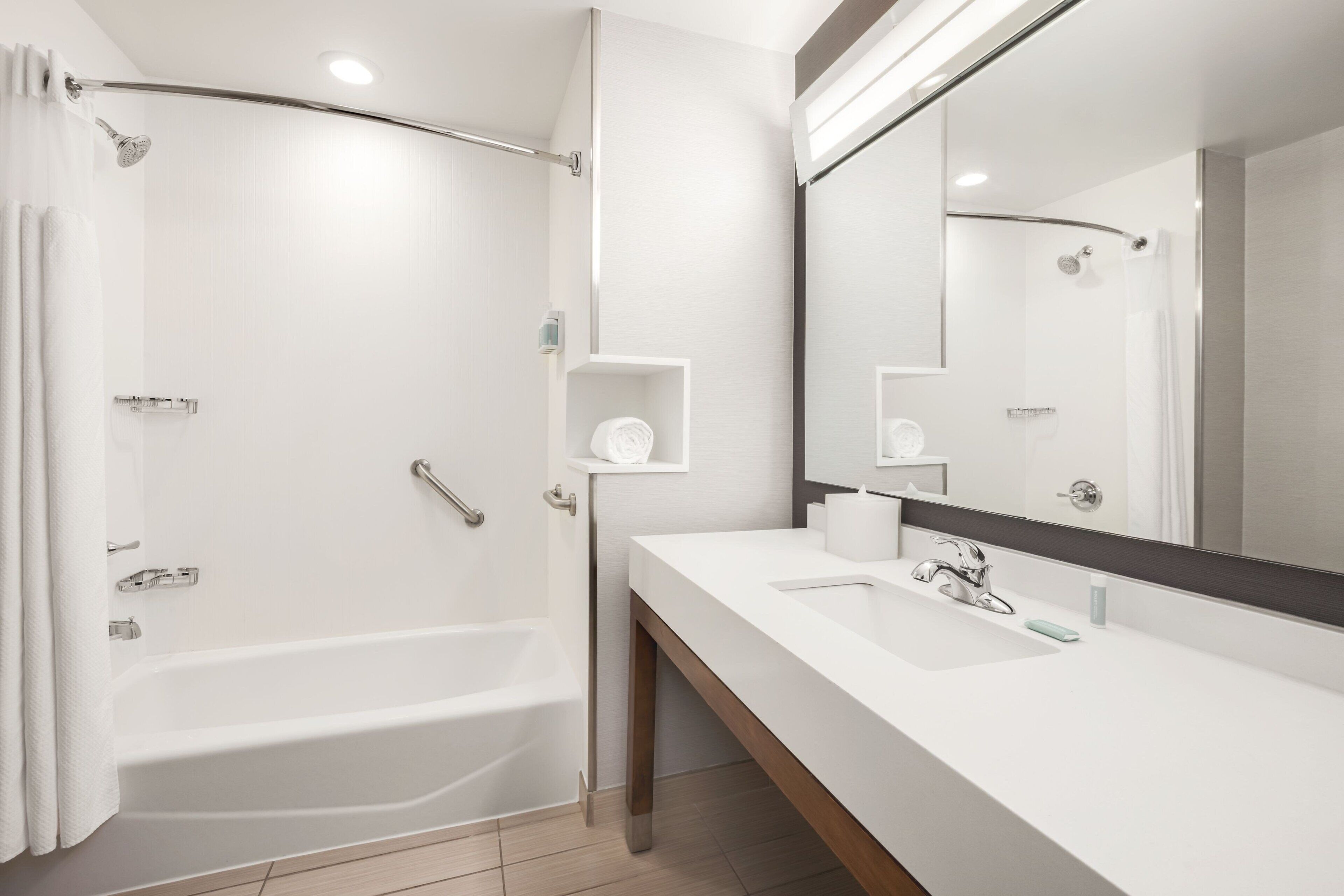 Ein modernes Badezimmer mit einer Badewanne, einem großen Spiegel und einem Waschtisch.