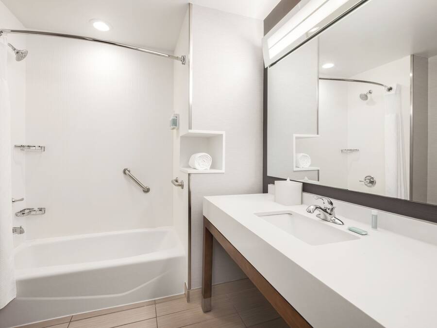 Ein modernes Badezimmer mit einer Badewanne, einem großen Spiegel und einem Waschtisch.
