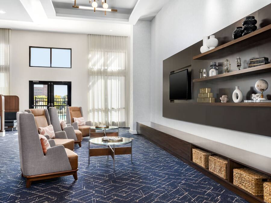 A modern living room with a large TV, comfortable seating, and a decorative shelf.