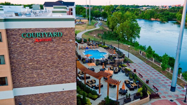 Un hotel Courtyard Marriott con piscina en la azotea, zona de estar al aire libre y vistas a un río.